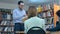 Young male teacher with book talking to students in library