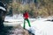 Young male tourist crosses a river in the mountains in winter