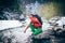 Young male tourist drinks fresh water from a river in the mountains.