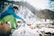 Young male tourist drinks hot coffee from a thermos near a river in the mountains