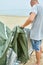 Young male tourist puts a green tent in the beach coast . The man sets up a camp on a hike