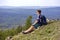 A young male tourist sits on the top of the sugomak mountain and looks into the distance at the Ural mountains