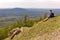 A young male tourist sits on the top of the sugomak mountain and looks into the distance at the Ural mountains