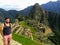 A young male tourist standing posing for a photo with Machu Picchu in the background early in the morning