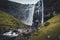 Young male tourist traveler standng in front of the Fossa Waterfall on island Bordoy. This is the highest waterfall in