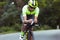 Young male triathlete riding a bicycle on the open road. Professional sportsman is engaged in triathlon on bright summer