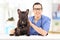 Young male veterinarian doctor posing with bulldog in his office