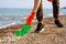 Young male volunteer picks up plastic garbage on the ocean coast. A man collects waste on the seaside to save ecology and protect