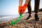 Young male volunteer picks up plastic garbage on the ocean coast. A man collects waste on the seaside to save ecology and protect