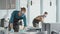 Young male waiters in protective workwear cleaning tables in restaurant