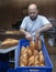 Young male worker working in bakery. She puts bread on shelf. Fresh Loaf Bread from the oven. Transportation of baking