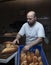 Young male worker working in bakery. She puts bread on shelf. Fresh Loaf Bread from the oven. Transportation of baking