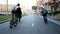 Young males friends on bikes ride along empty narrow road in city on sunny day.