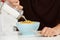 Young Man Adding Sugar To Breakfast Cereal