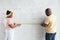 Young man of African ethnicity and his wife measuring length of wall bricks during home renovation