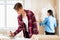 Young man applying adhesive to wallpaper