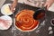 Young man applying sauce on pizza dough at table