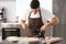 Young man applying sauce on pizza dough at table