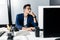 Young man architect in glasses dressed in a business suit sits at a desk in front of a computer in the office