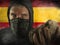 Young man as ultra and extremist Spanish nationalism defender. violent protester in face mask holding a brick at fighting riot in