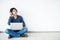 Young man asian sitting on the floor with using computer laptop smiling and listening nice music and feel relieved from stressed