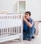 Young man assembling baby bed with instruction manual