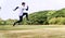 Young man athlete runner with energy exercise training and jumping outdoors with big green tree in the public park.