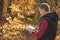 Young man in the autumn forest and reading book. Mental recreation in nature. Quiet country life. Escapism. Digital