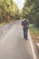 A young man with a backpack behind him is walking along an empty autumn road. Travel, hipster. Walk in the fall, autumn trees.