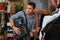 Young man with backpack feeling nervous while being in clothes shop