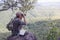 Young man with backpack and holding a binoculars sitting on top of mountain, Hiking and tourism concepts