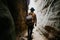 Young man with a backpack stands at a cave exit. Extreme summer vacation