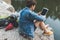 young man with backpack using tablet on nature while sitting on rocky