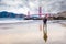 Young man on Baker Beach and a magnificent view of the Golden Gate Bridge at dawn