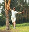 young man balancing his arms walk on a loose rope tied between two trees, male training slack rope walking, slacklining outdoors