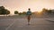 Young man balancing skateboard at evening back view. Active guy riding longboard