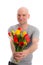 Young man with bald head and bunch of tulips