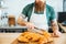 Young man barista with beard taking croissant using tongs