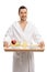Young man in bathrobe holding tray with fruit, drink and cereal