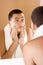 Young man in the bathroom\'s mirror after shaving