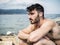 Young man at beach listening to music with earphones