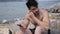 Young man at beach listening to music with earphones