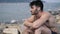 Young man at beach listening to music with earphones