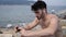 Young man at beach listening to music with earphones