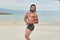 Young man on the beach, young muscular man exercising on the beach, young muscular man doing bodibuilding exercises on the beach,