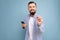 A young man with a beard on the background of a blue wall shows a gesture delicious