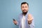 A young man with a beard on the background of a blue wall shows a gesture delicious close-up portrait