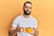 Young man with beard drinking a cup coffee looking at the camera blowing a kiss being lovely and sexy