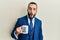 Young man with beard drinking from i am the boss coffee cup scared and amazed with open mouth for surprise, disbelief face