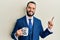 Young man with beard drinking from i am the boss coffee cup smiling happy pointing with hand and finger to the side